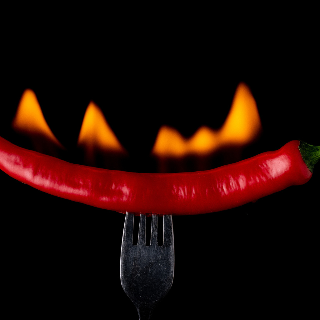 Жгучий красный перец на вилке на черном фоне