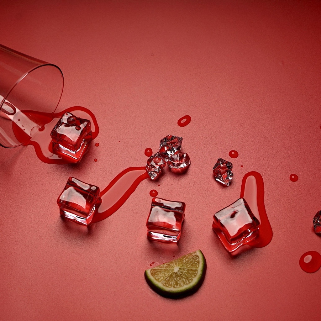 Кубики льда на красном фоне с кусочком лайма и стаканом