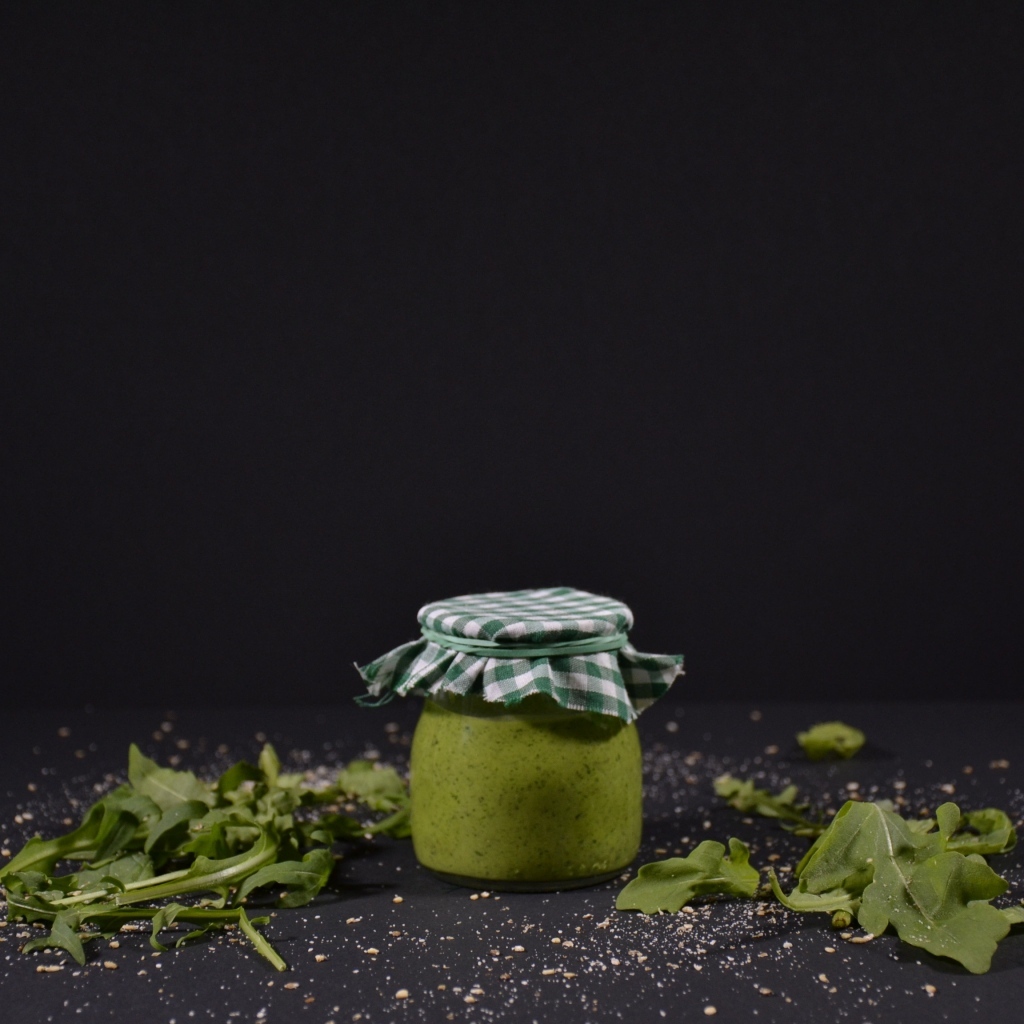 Банка соуса песто на черном фоне
