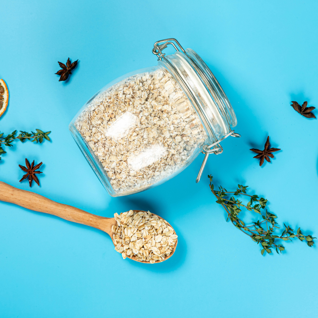 Банка с овсяными хлопьями и ложкой на голубом фоне