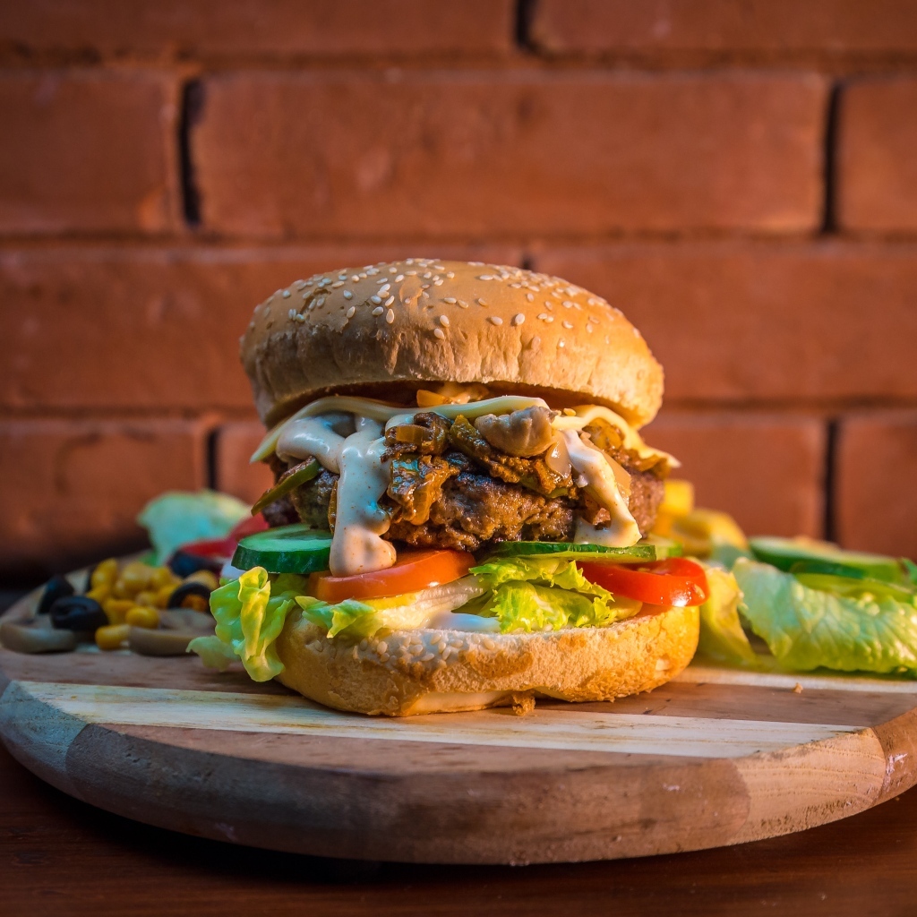 Большой аппетитный гамбургер на фоне стены