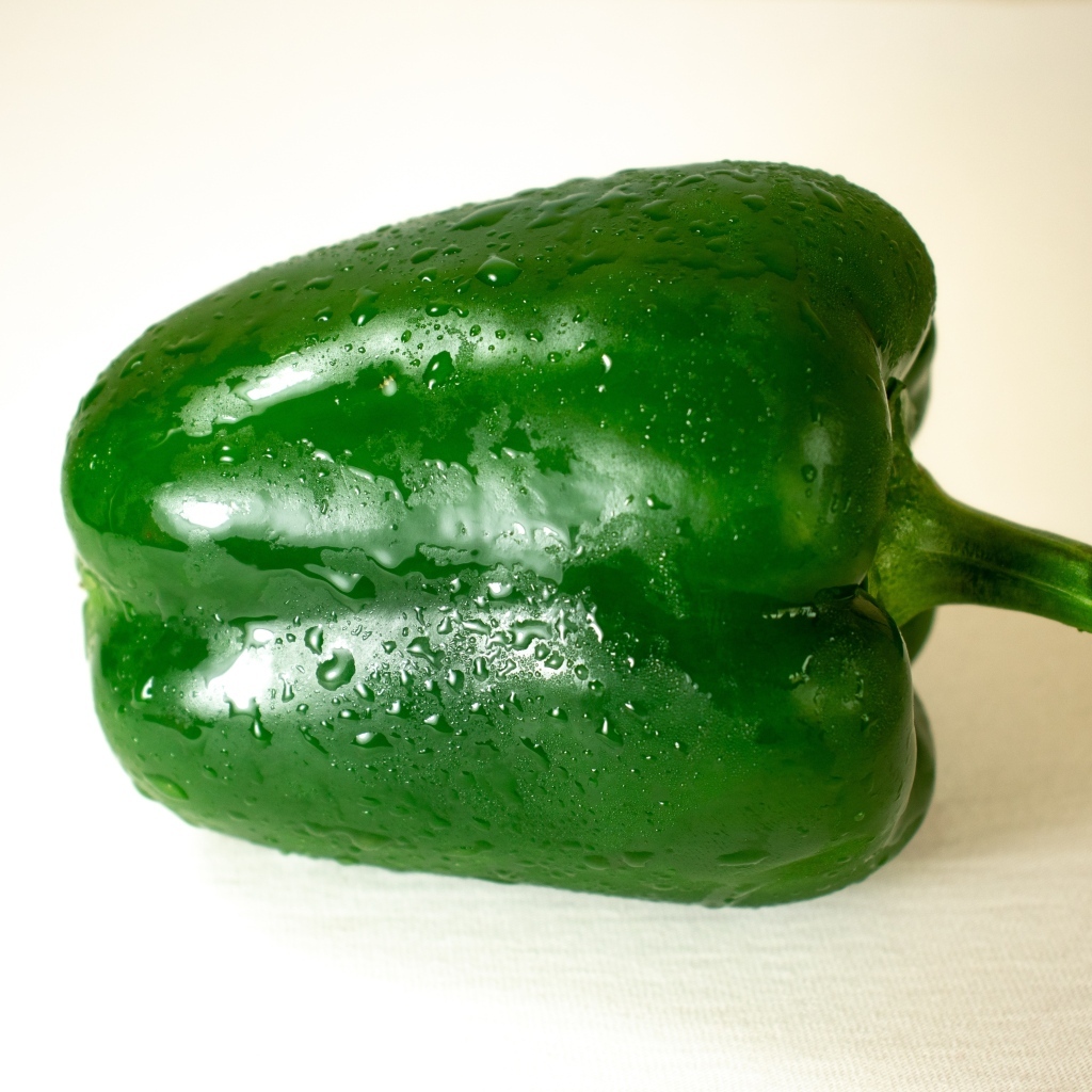 Крупный зеленый перец на белом фоне
