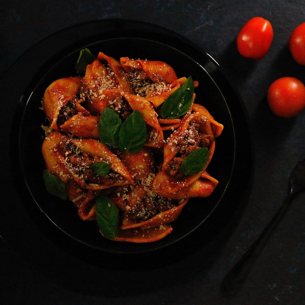 Большие макароны с фаршем в черной тарелке