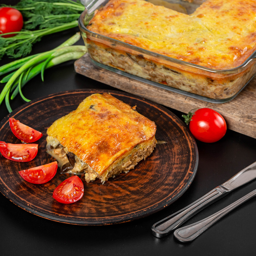 Лазанья на тарелке с помидорами и зеленью