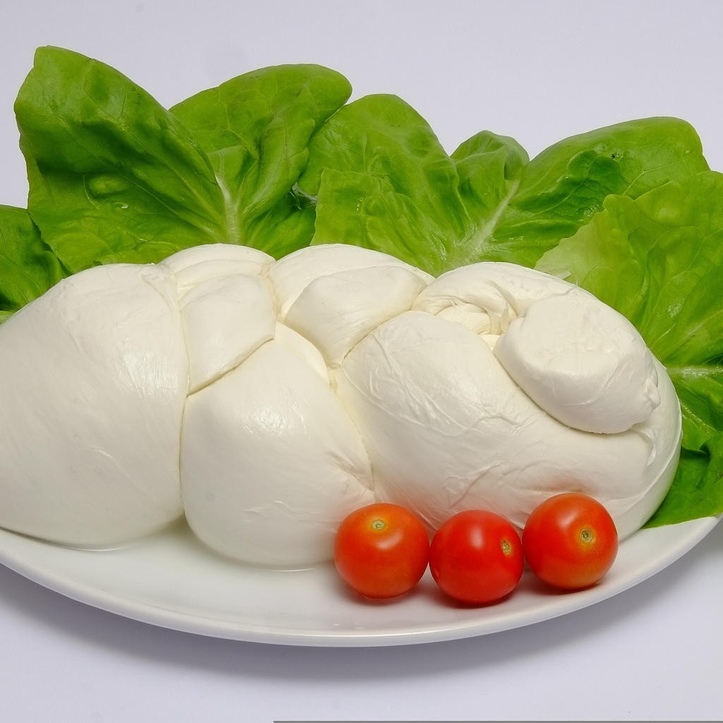 Сыр моцарелла на тарелке с листьями салата и помидорами