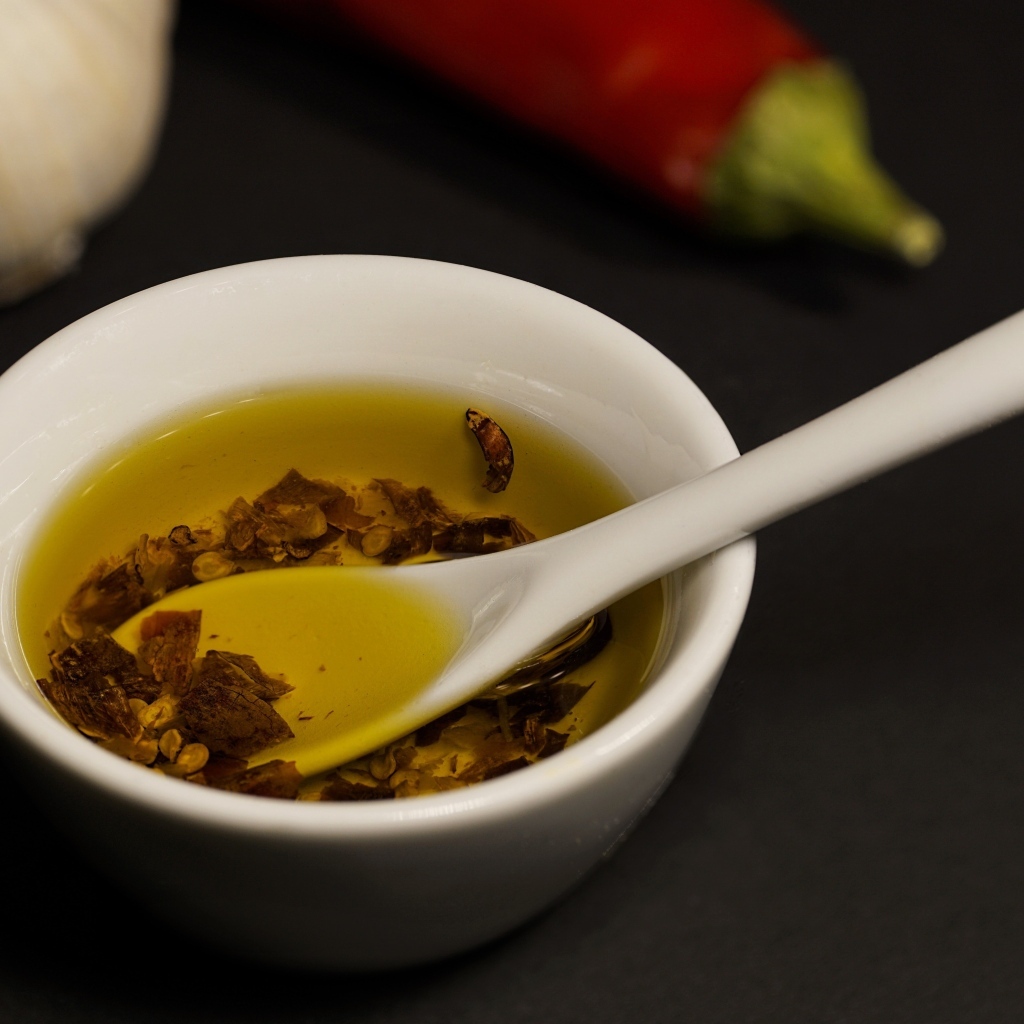 Оливковое масло в тарелке на столе с перцем и чесноком