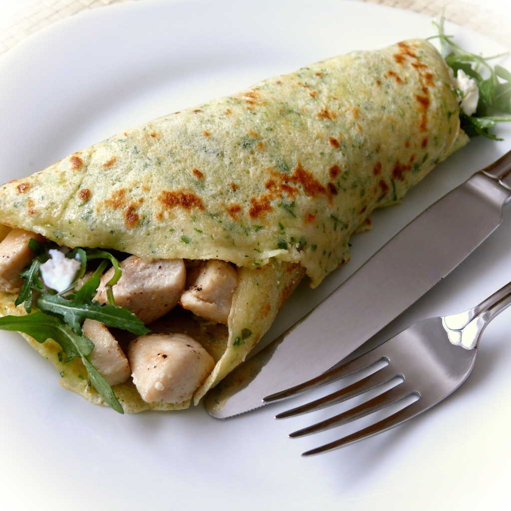 Блин с жареной курицей и рукколой на тарелке 