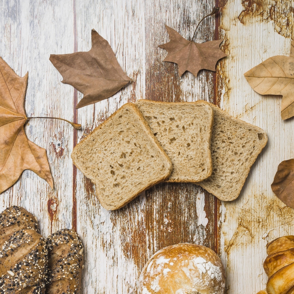Куски хлеба с листьями на деревянном столе