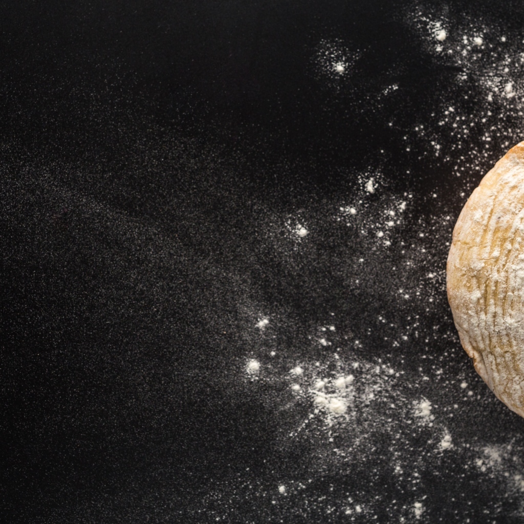 Сырое тесто на черном столе с мукой