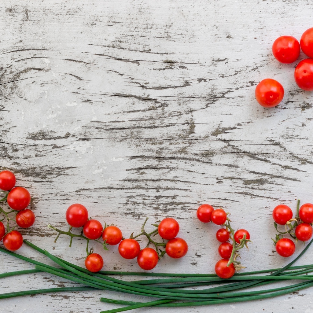 Красные помидоры с зеленым луком на деревянном столе