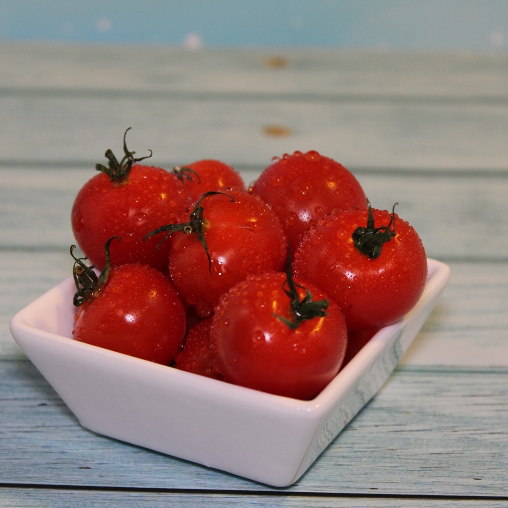 Красные мокрые помидоры в белой тарелке