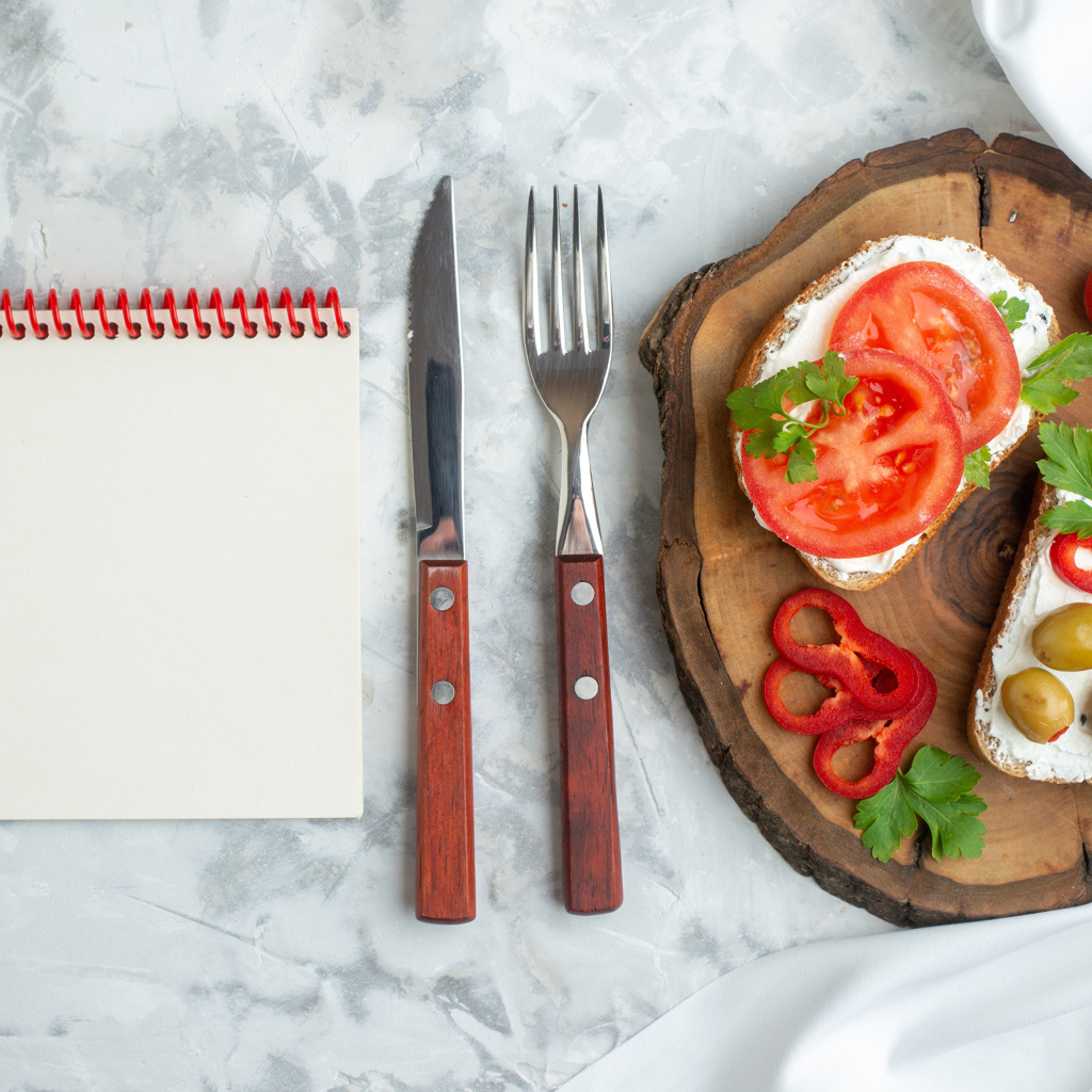 Бутерброды на столе со столовыми приборами и блокнотом