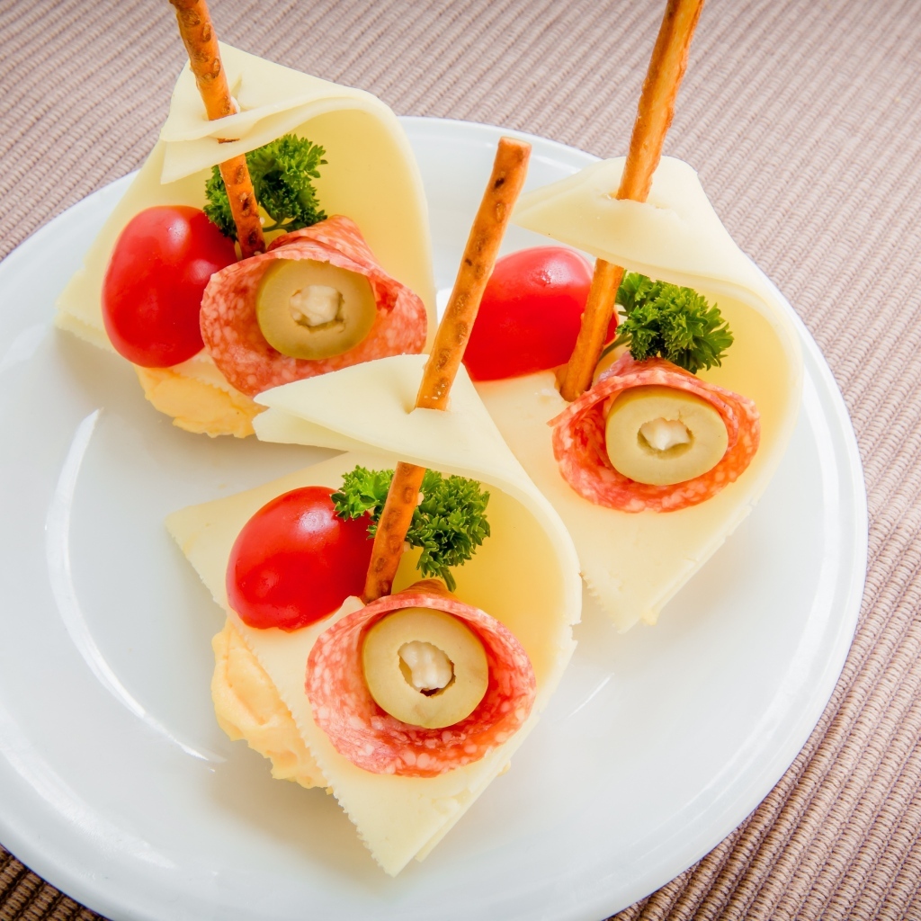 Бутерброды с колбасой, сыром и помидорами на белой тарелке