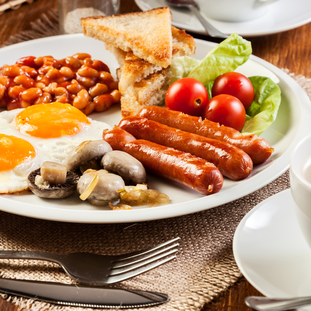 Яичница, сосиски и овощи на тарелке на завтрак