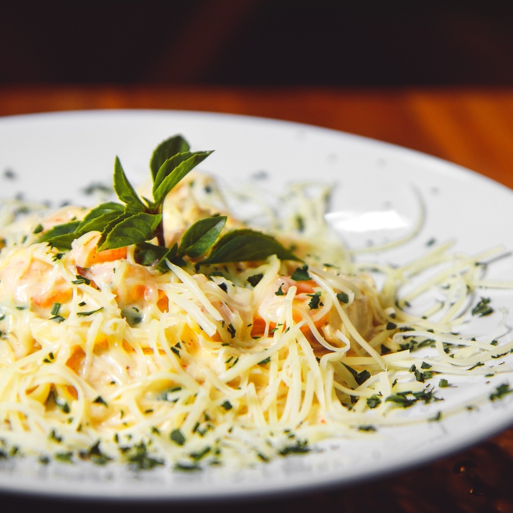 Спагетти с сыром и помидорами на белой тарелке