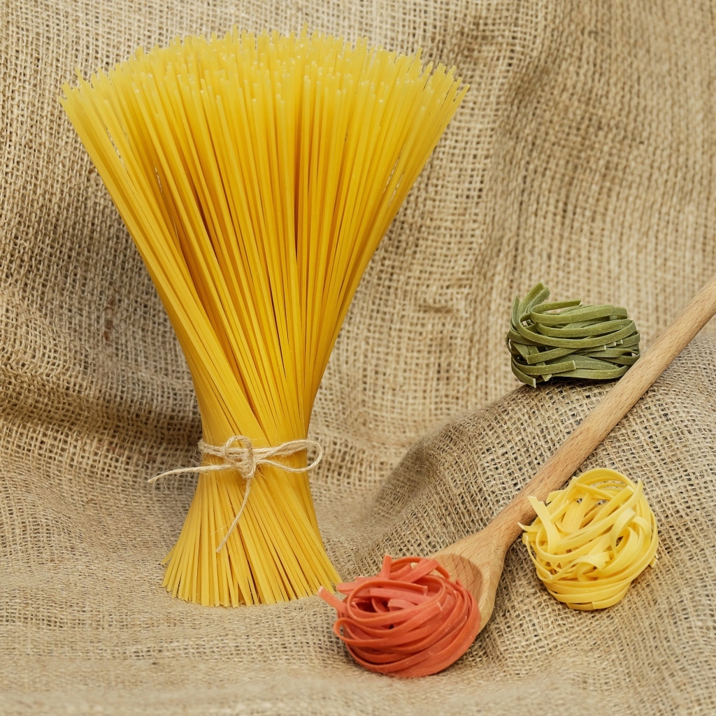 Спагетти с деревянной ложкой и макаронами на столе 