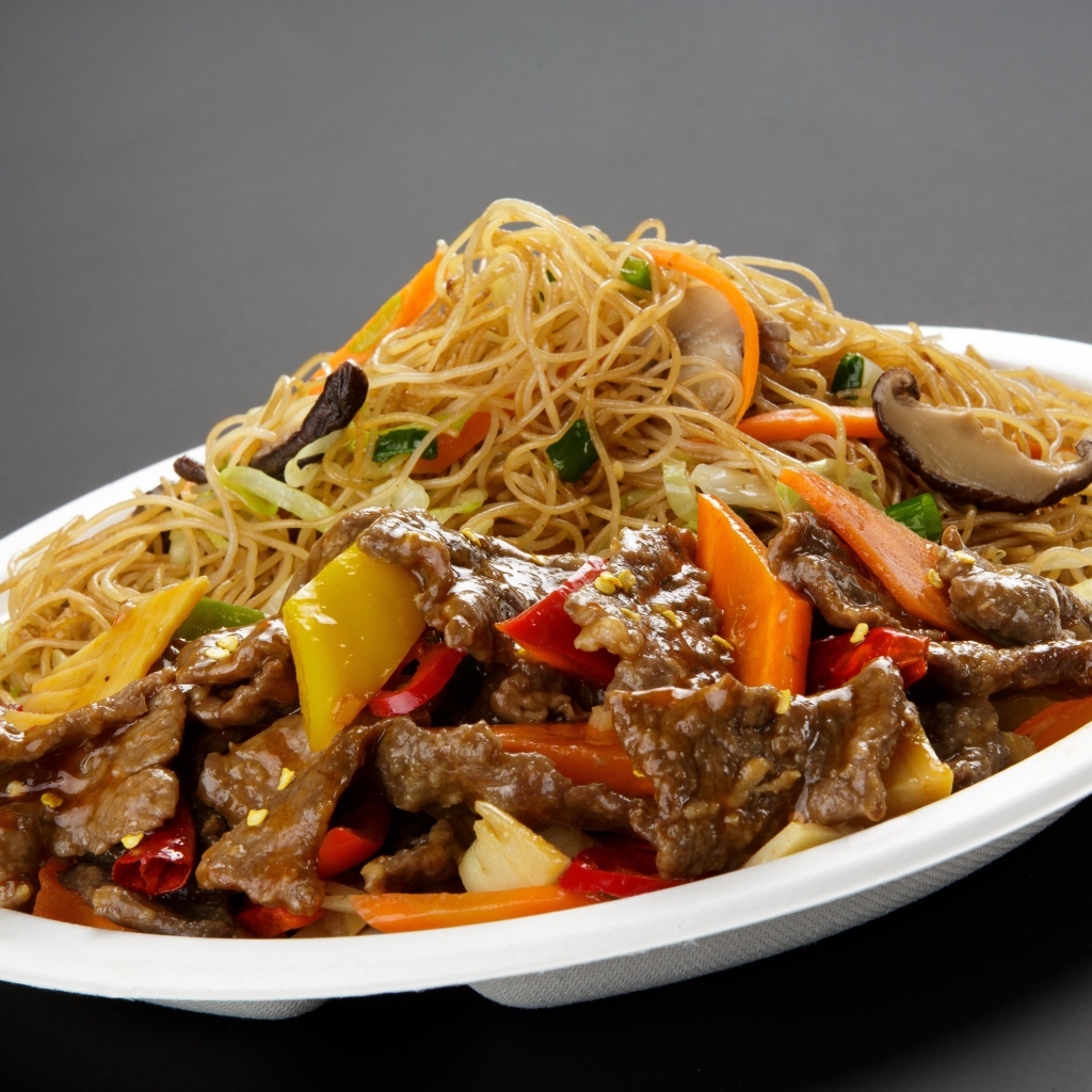 Острая лапша с грибами на белой тарелке на сером фоне