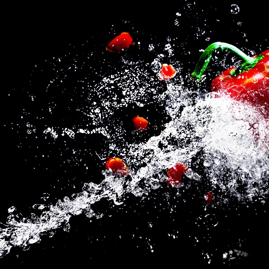 Сладкий красный перец в брызгах воды на черном фоне