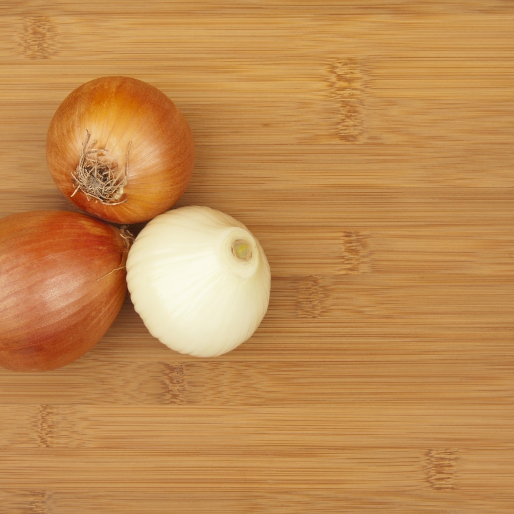 Три луковицы на деревянном столе