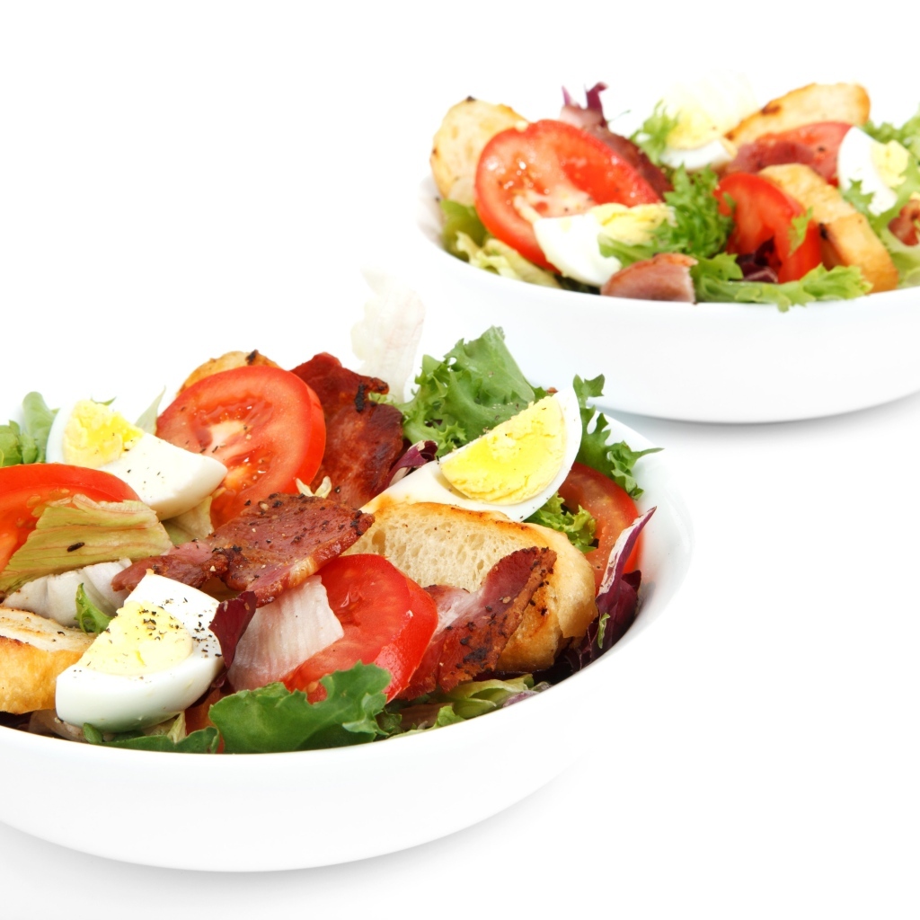 Две миски вкусного салата на белом фоне