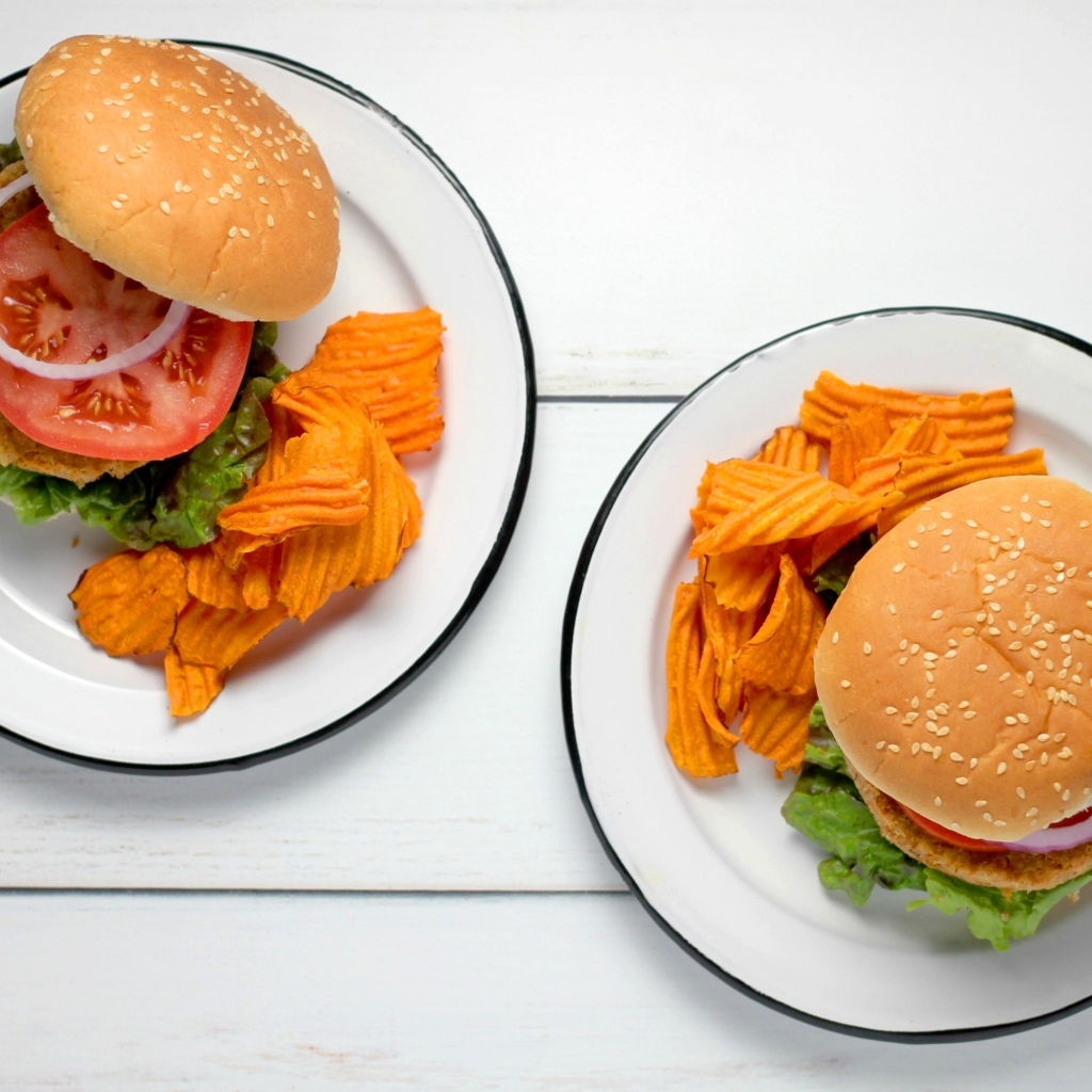Два гамбургера на тарелке с чипсами