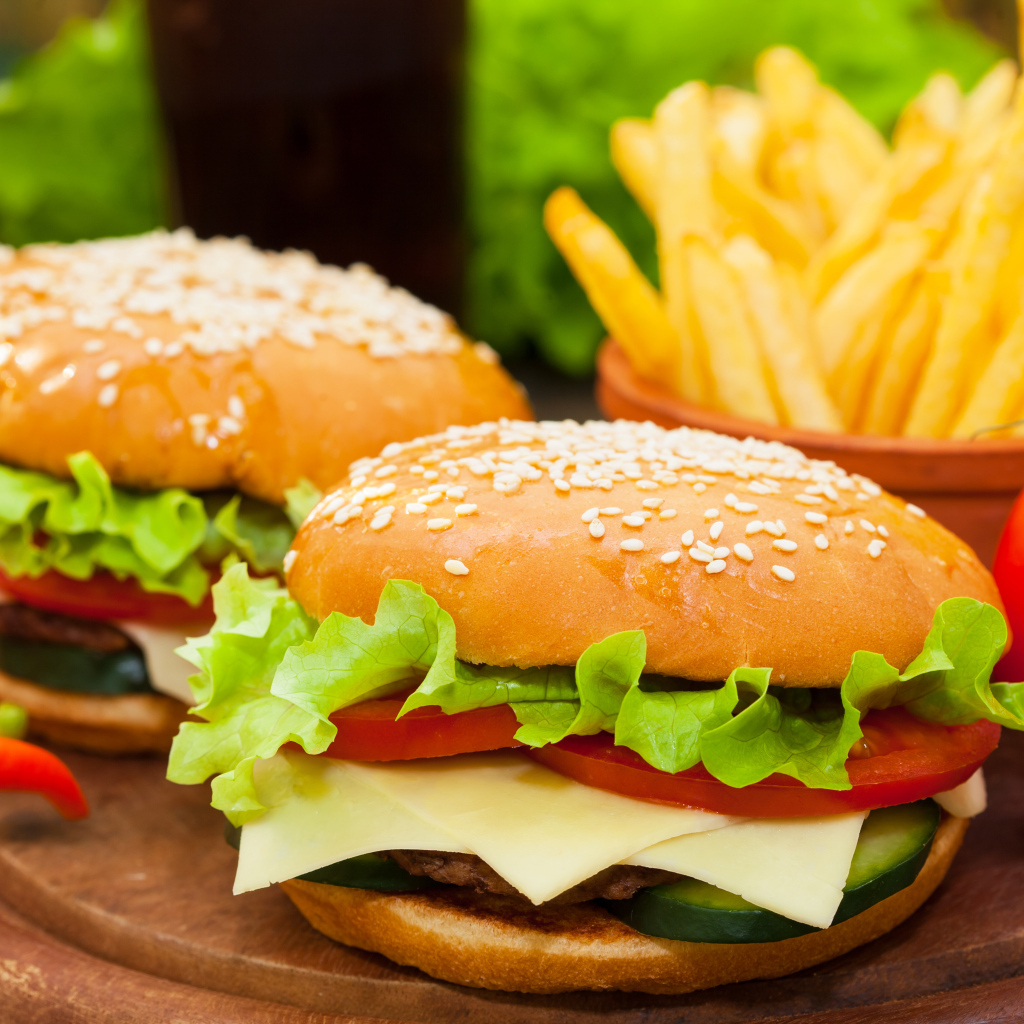 Два больших гамбургера на столе с картофелем фри