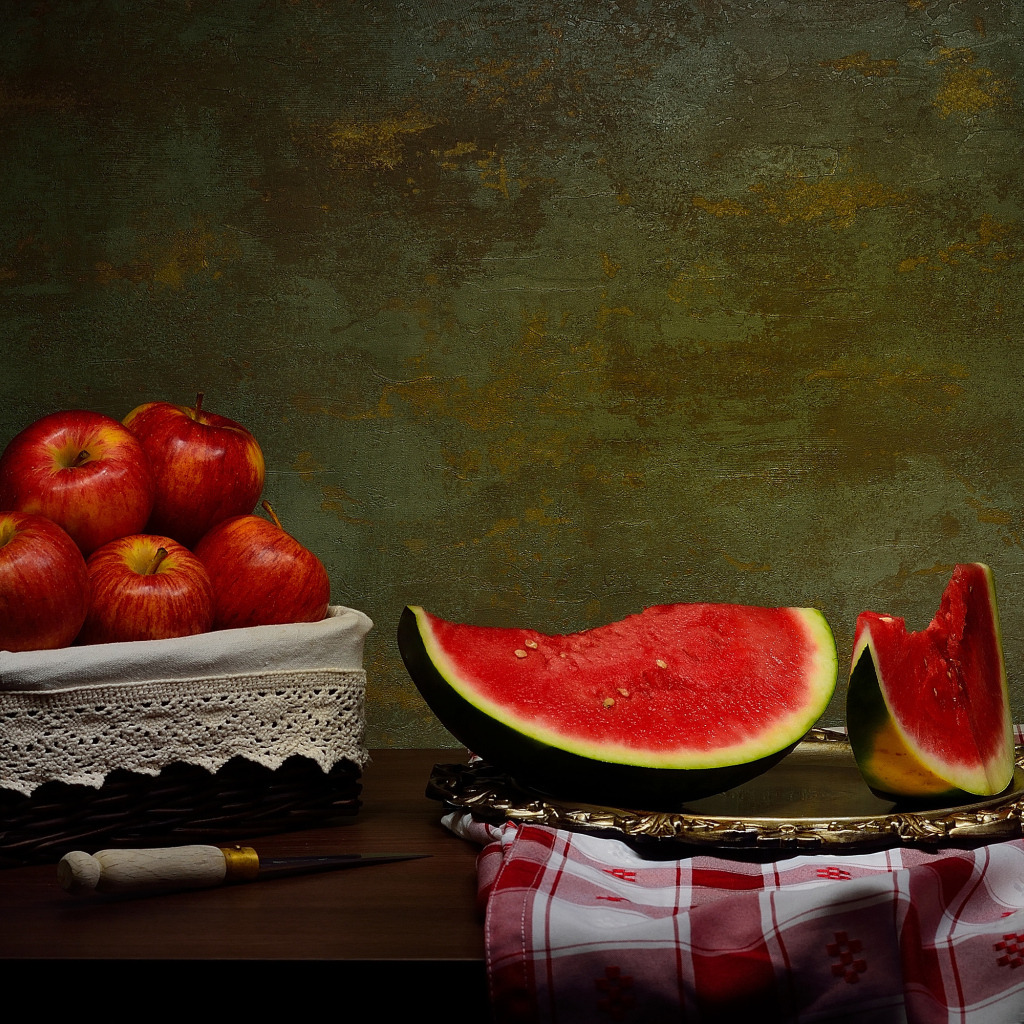 Скибки арбуза на столе с яблоками 