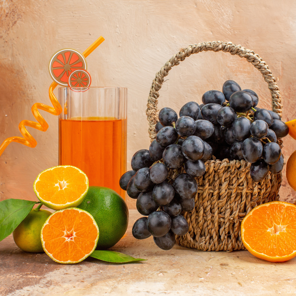 Корзина с виноградом на столе с апельсинами и лаймом