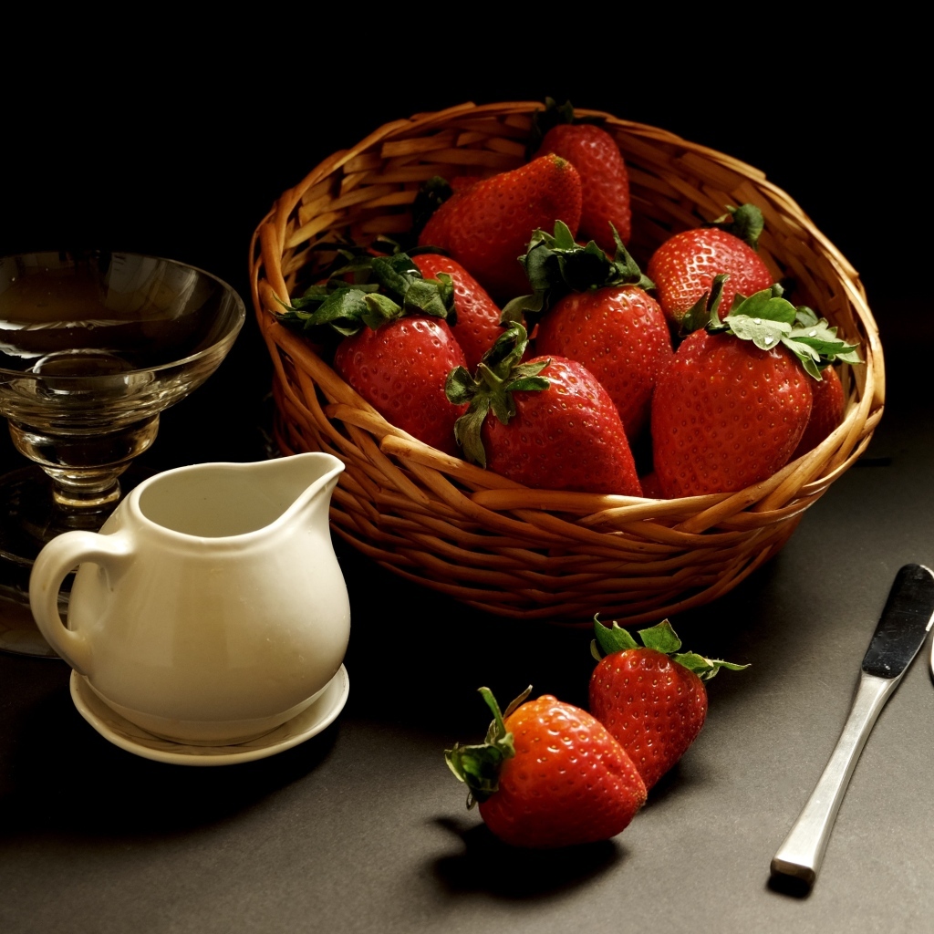 Корзина со спелой красной клубникой на столе с посудой