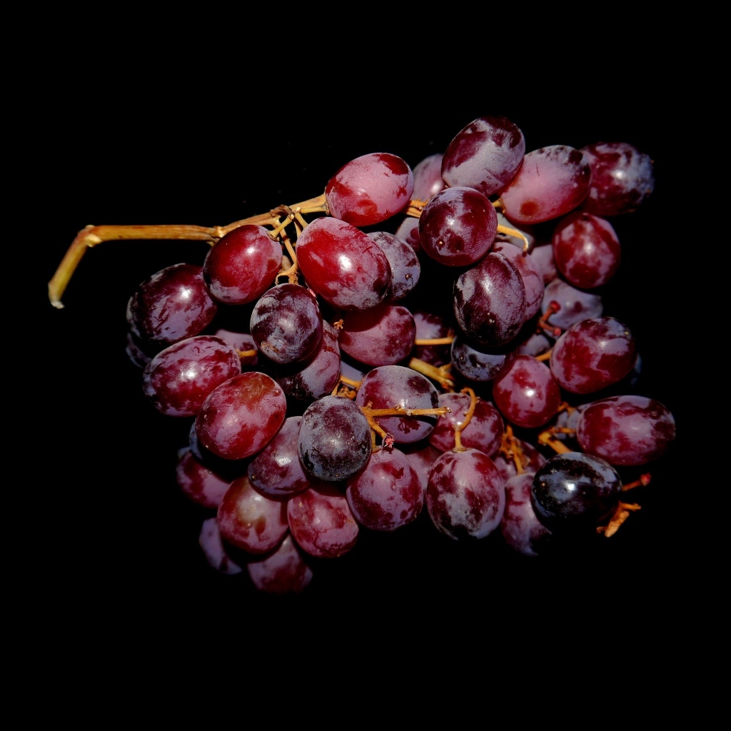 Гроздь розового винограда на черном фоне