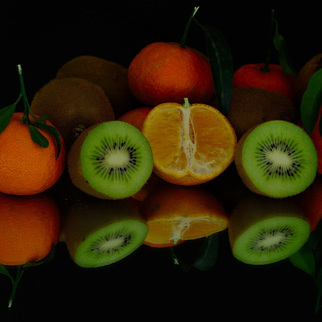 Цитрусовые фрукты на черной зеркальной поверхности