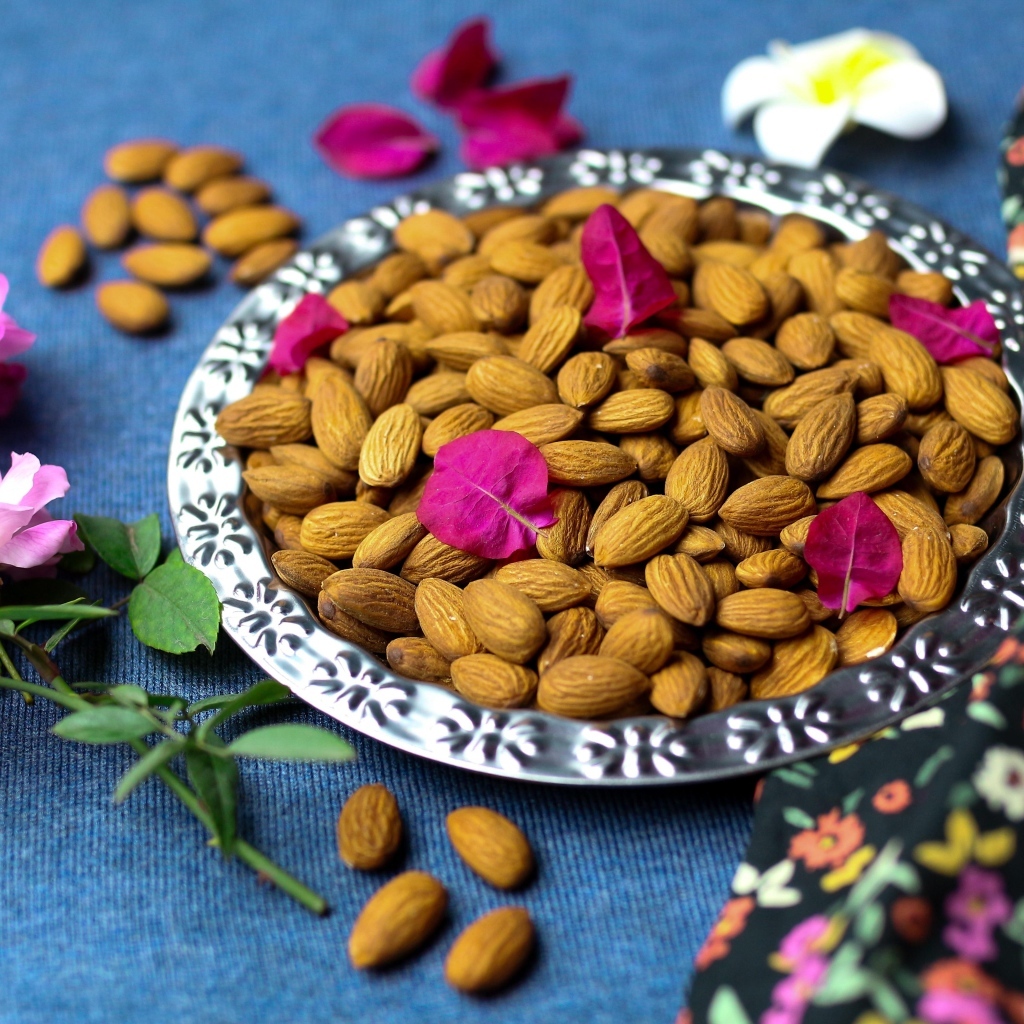 Вкусные миндальные орехи на тарелке с цветами