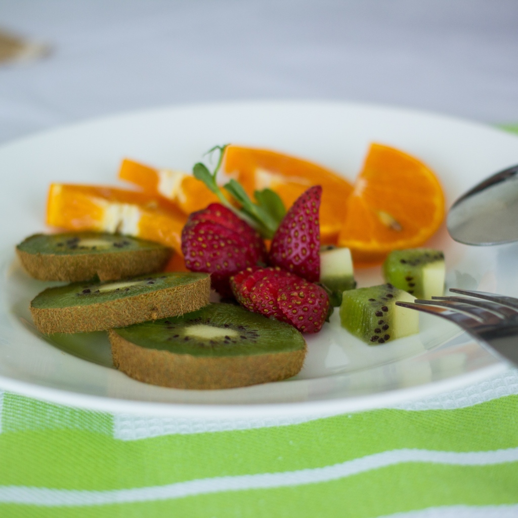 Свежие нарезанные фрукты на тарелке с вилкой