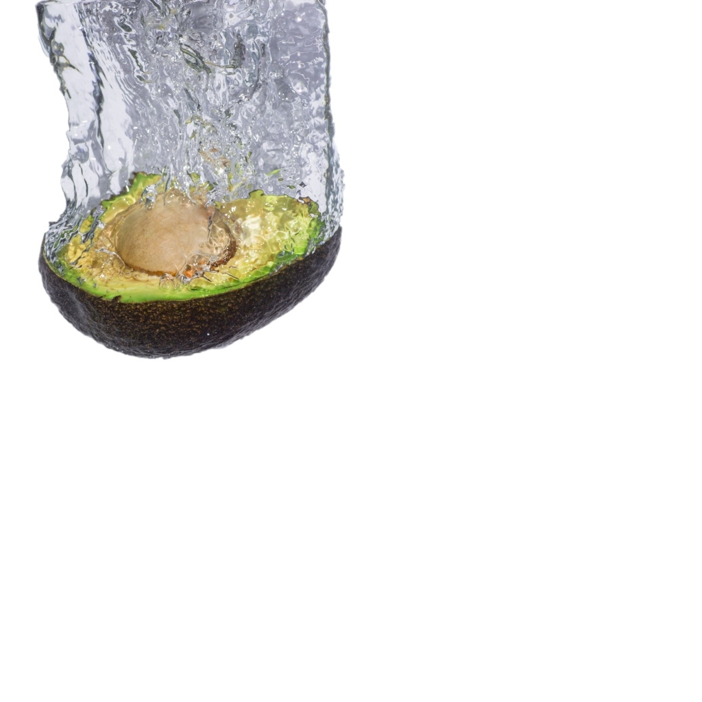 Половина авокадо падает в воду на белом фоне