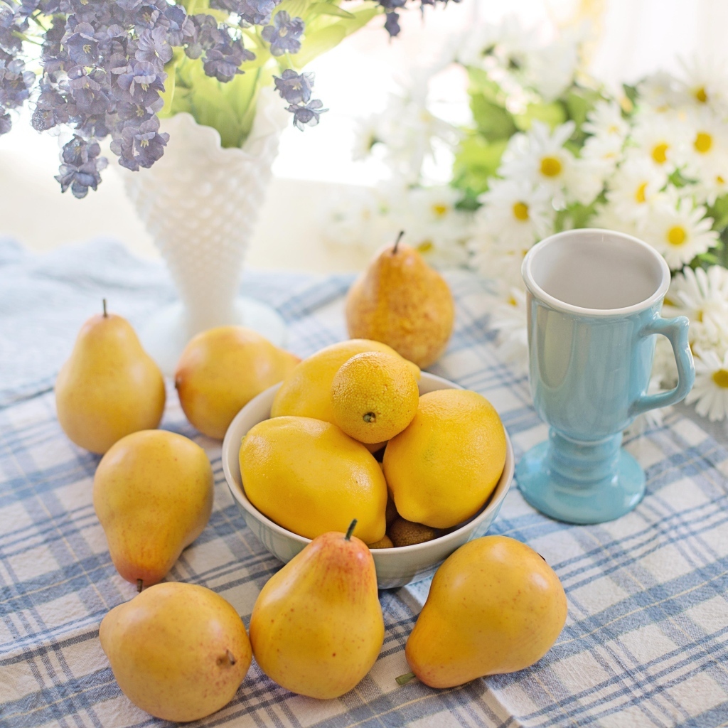 Лимоны и груши на столе с цветами