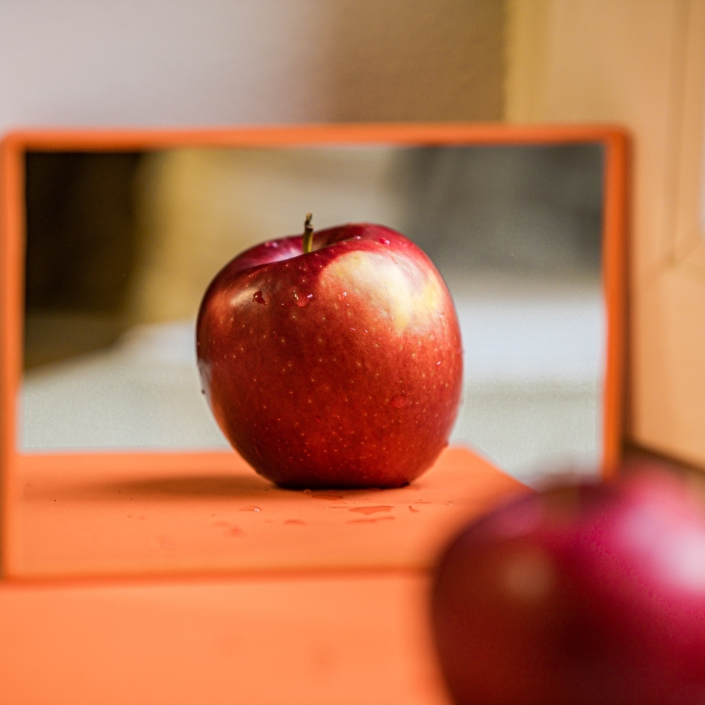 Больше красное яблоко отражается в зеркале 