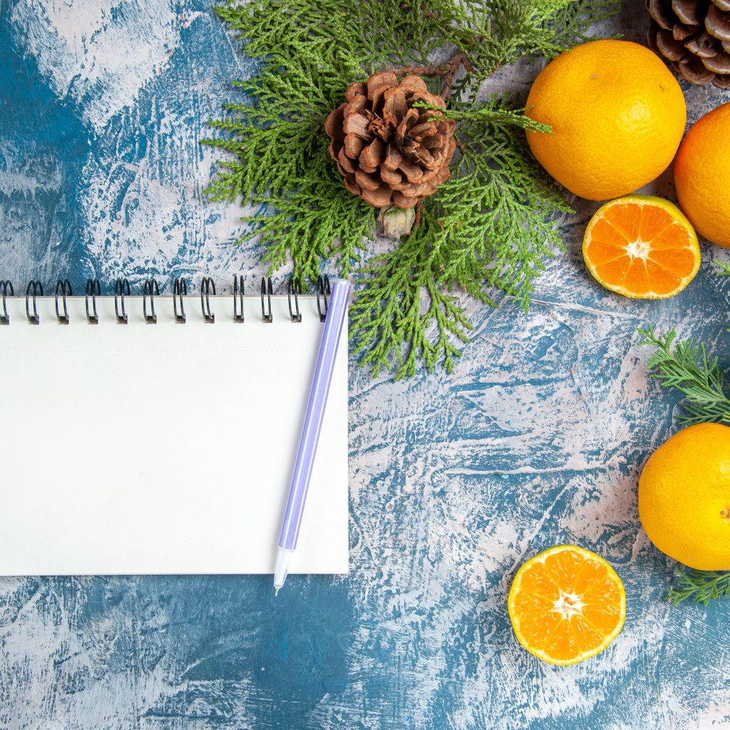 Блокнот на столе с мандаринами и ветками