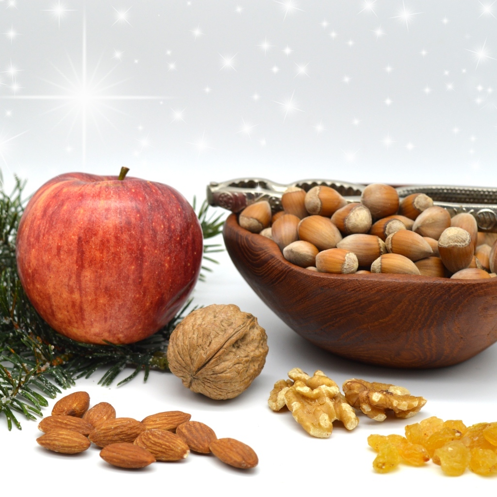Орехи с яблоком и еловой веткой на столе