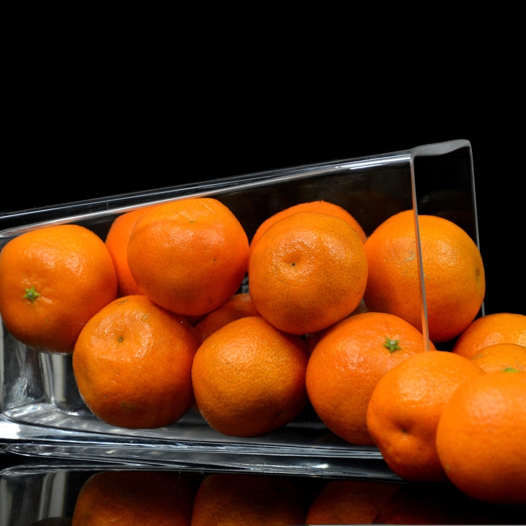 Оранжевые мандарины в стакане на черном фоне