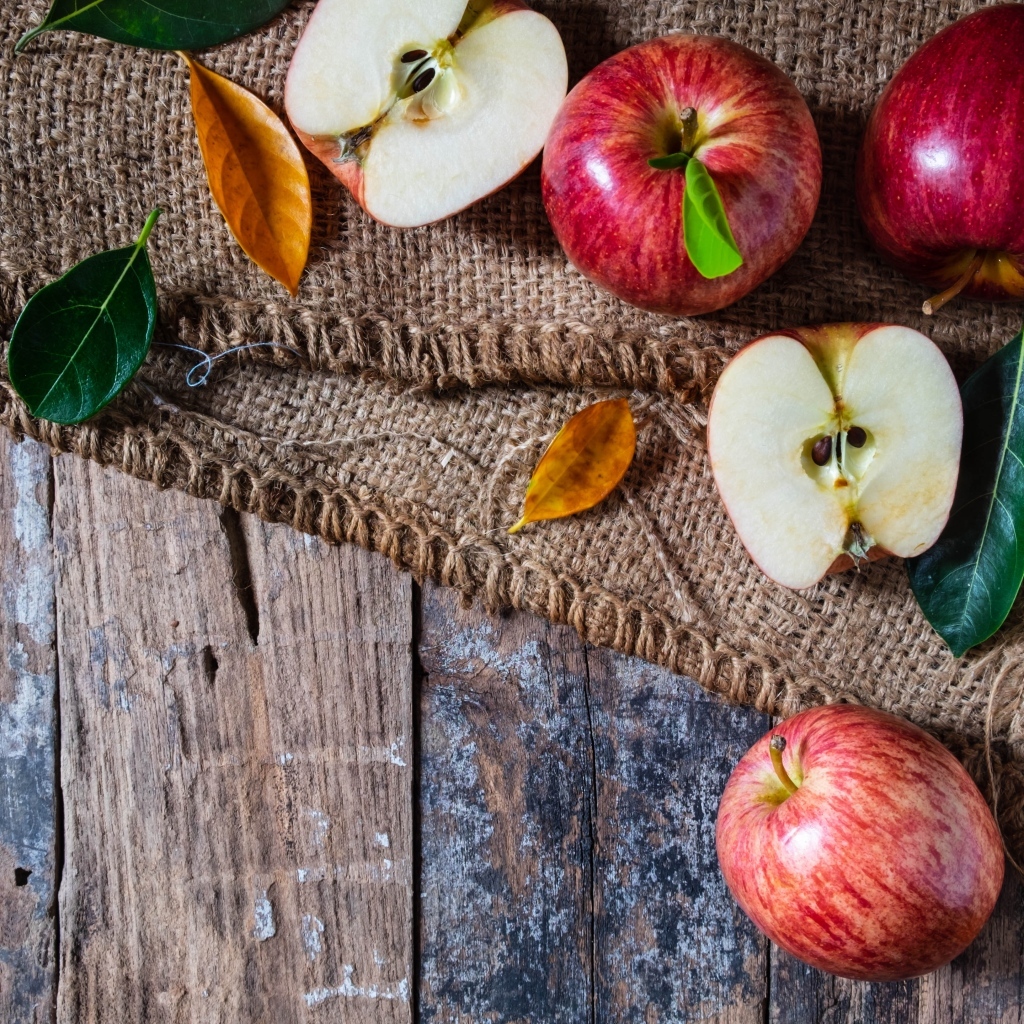 Спелые красные яблоки на столе с мешком