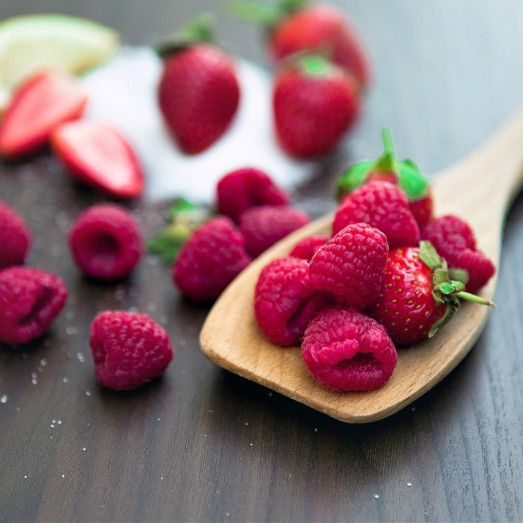 Спелая красная малина с деревянной ложкой на столе