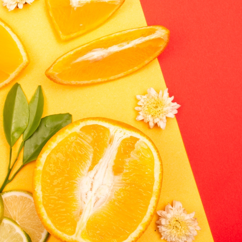 Кусочки апельсина и лайма на разноцветной поверхности 