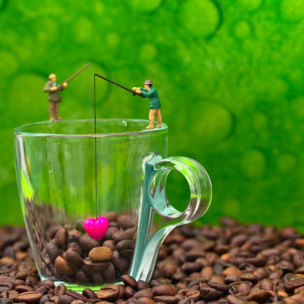 Две фигурки на стеклянной чашкой с кофейными зернами