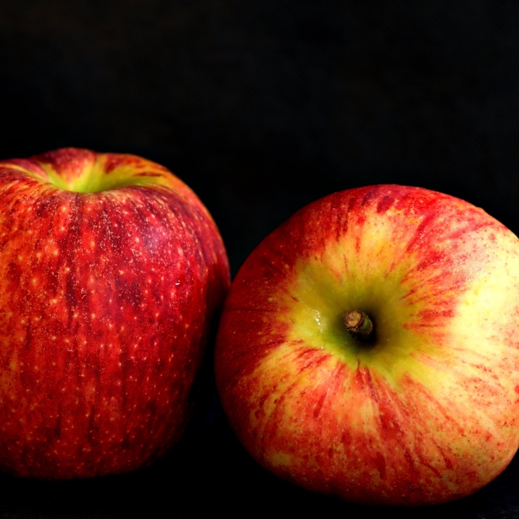 Два больших спелых красных яблока на черном фоне