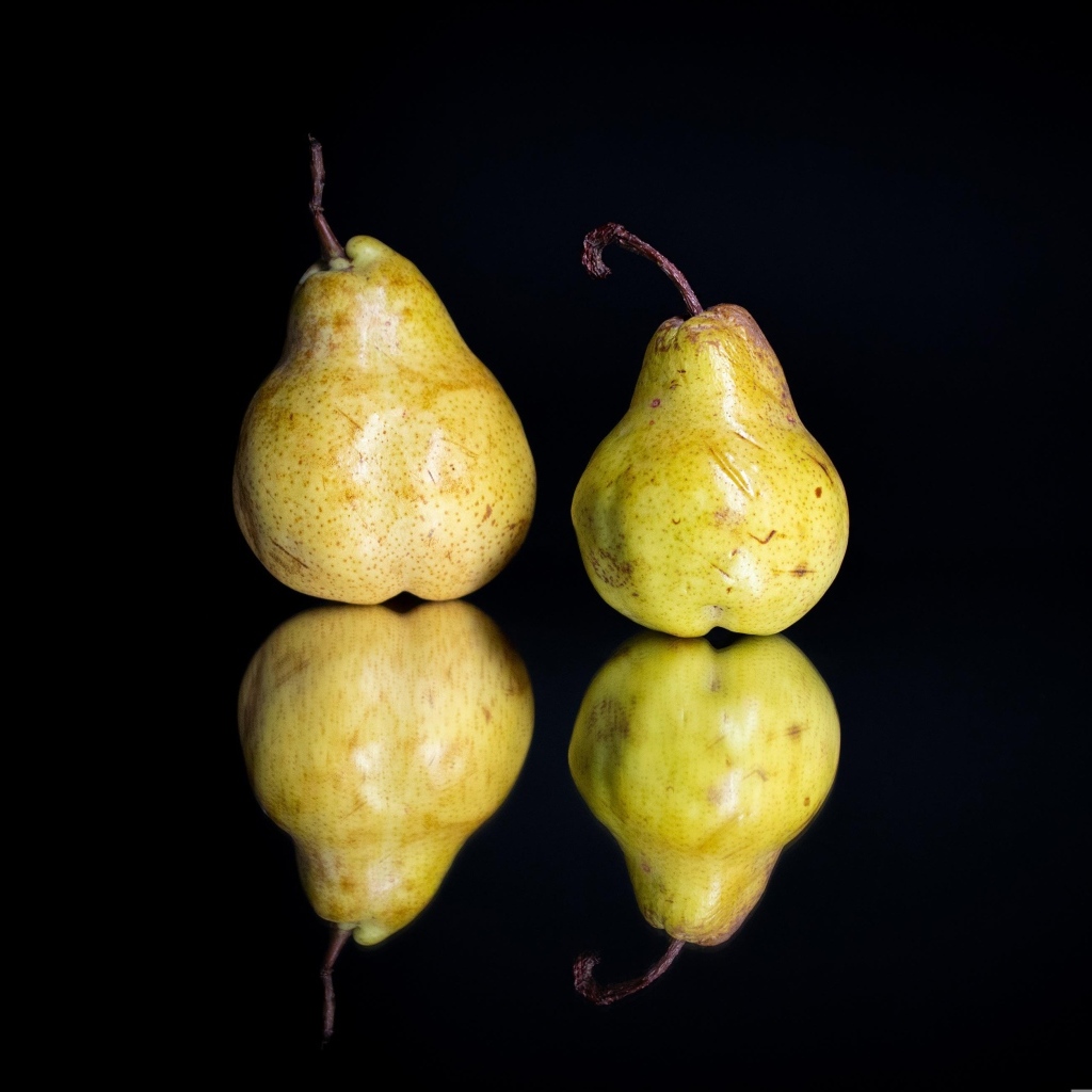 Две груши отражаются в зеркальной поверхности 