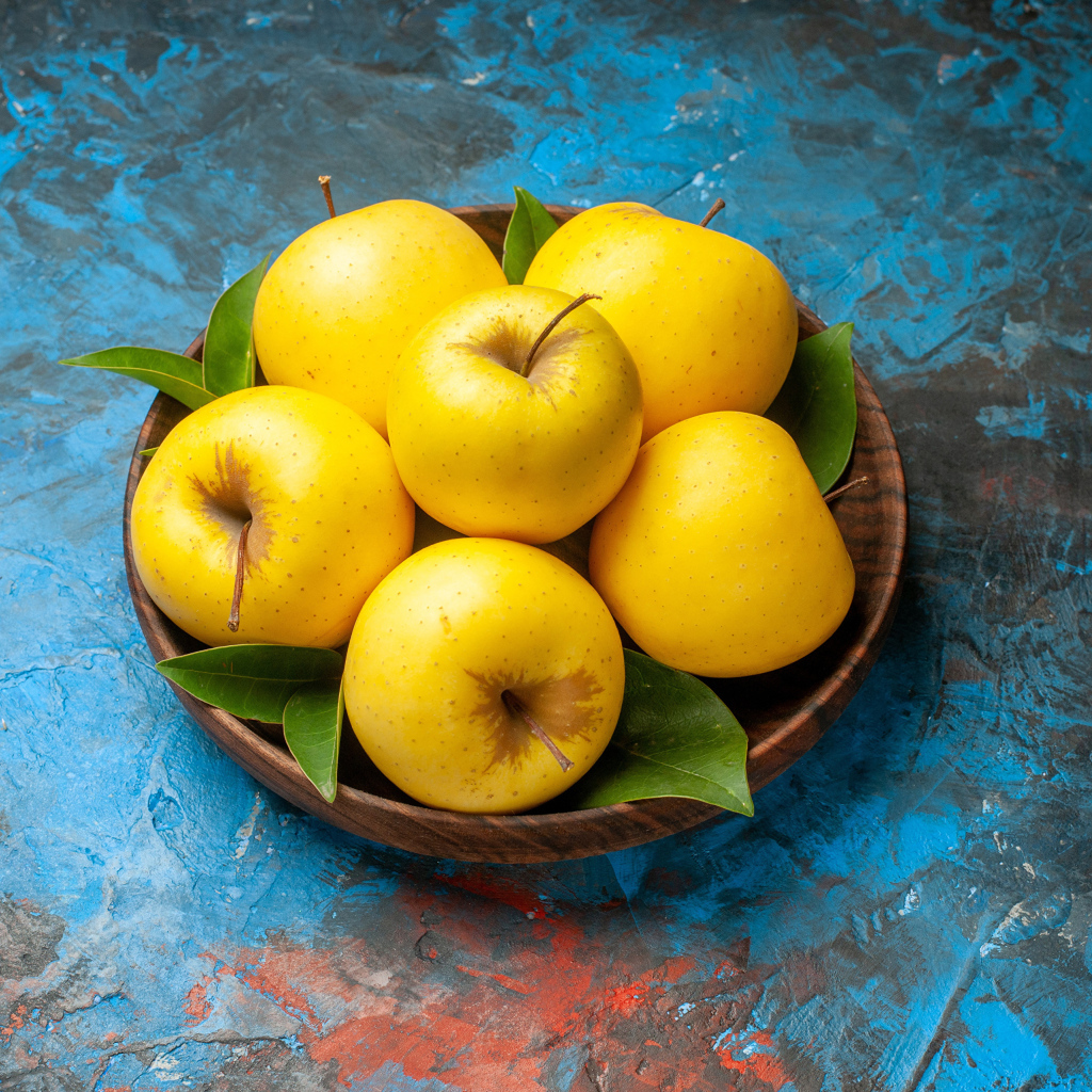 Деревянная тарелка с яблоками на столе