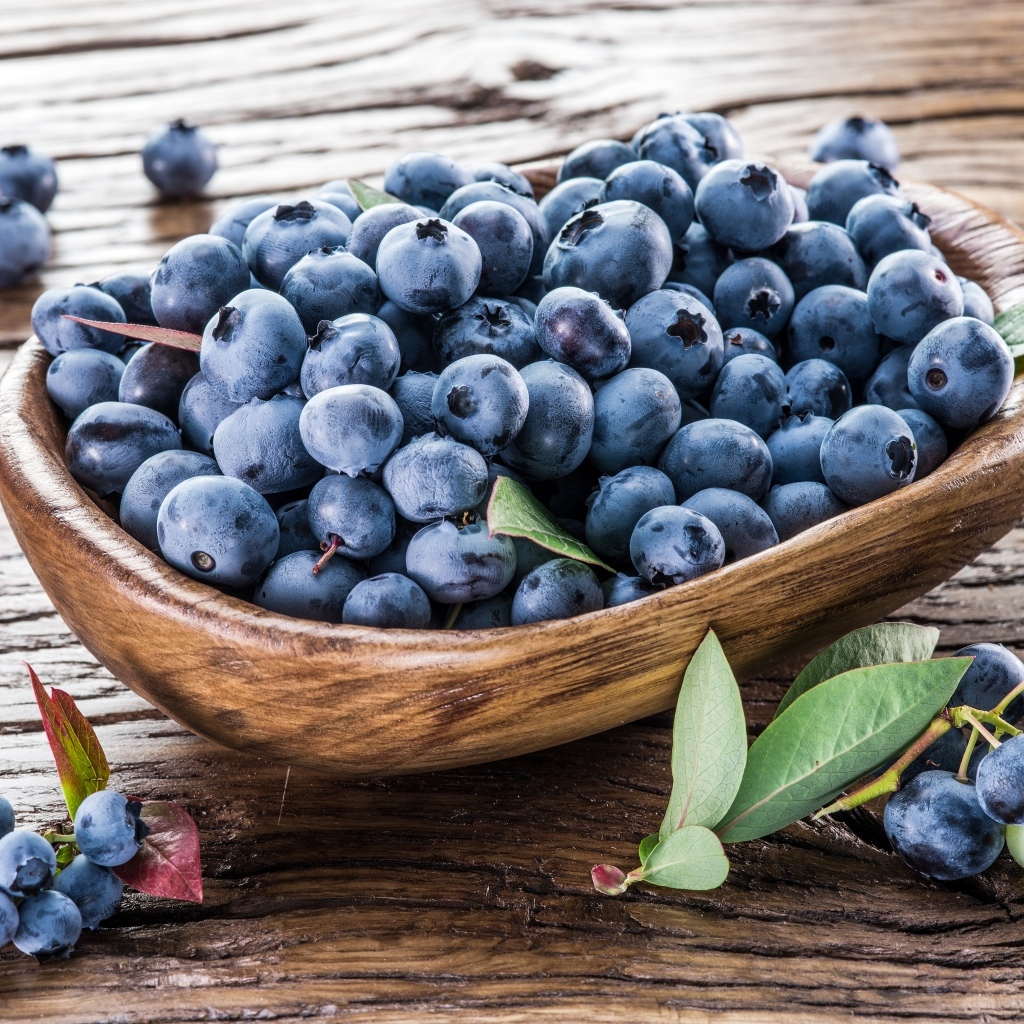 Деревянная тарелка с ягодами черники на столе