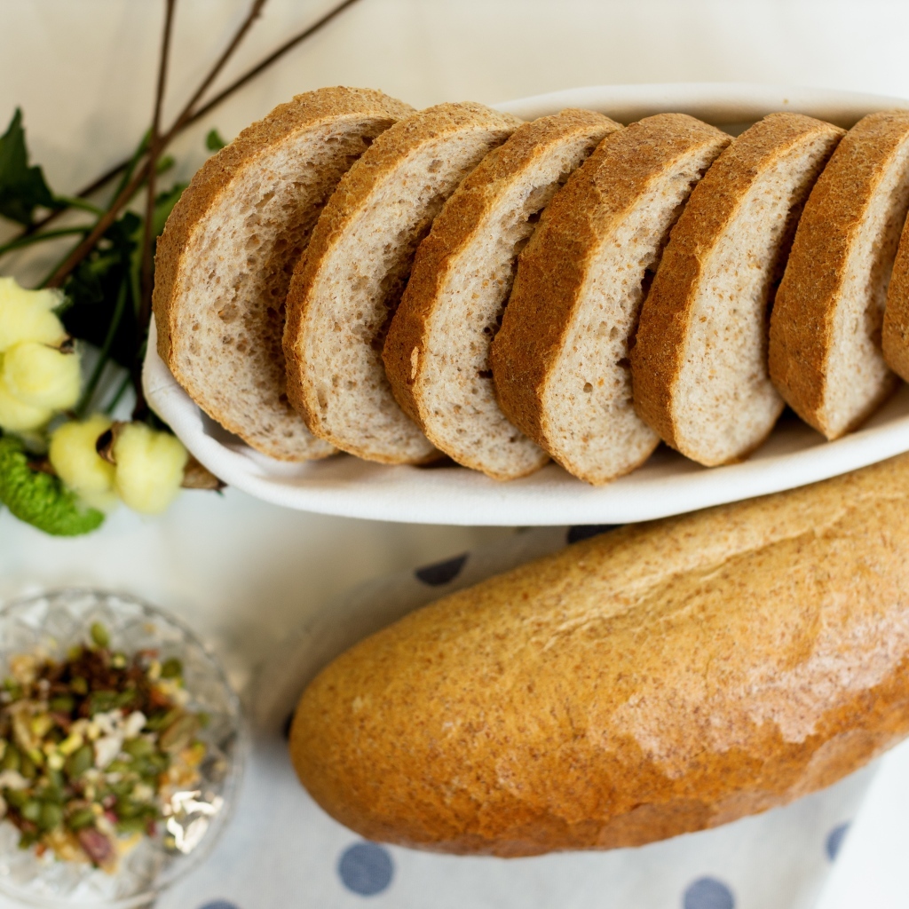 Батон нарезанный на столе с цветами