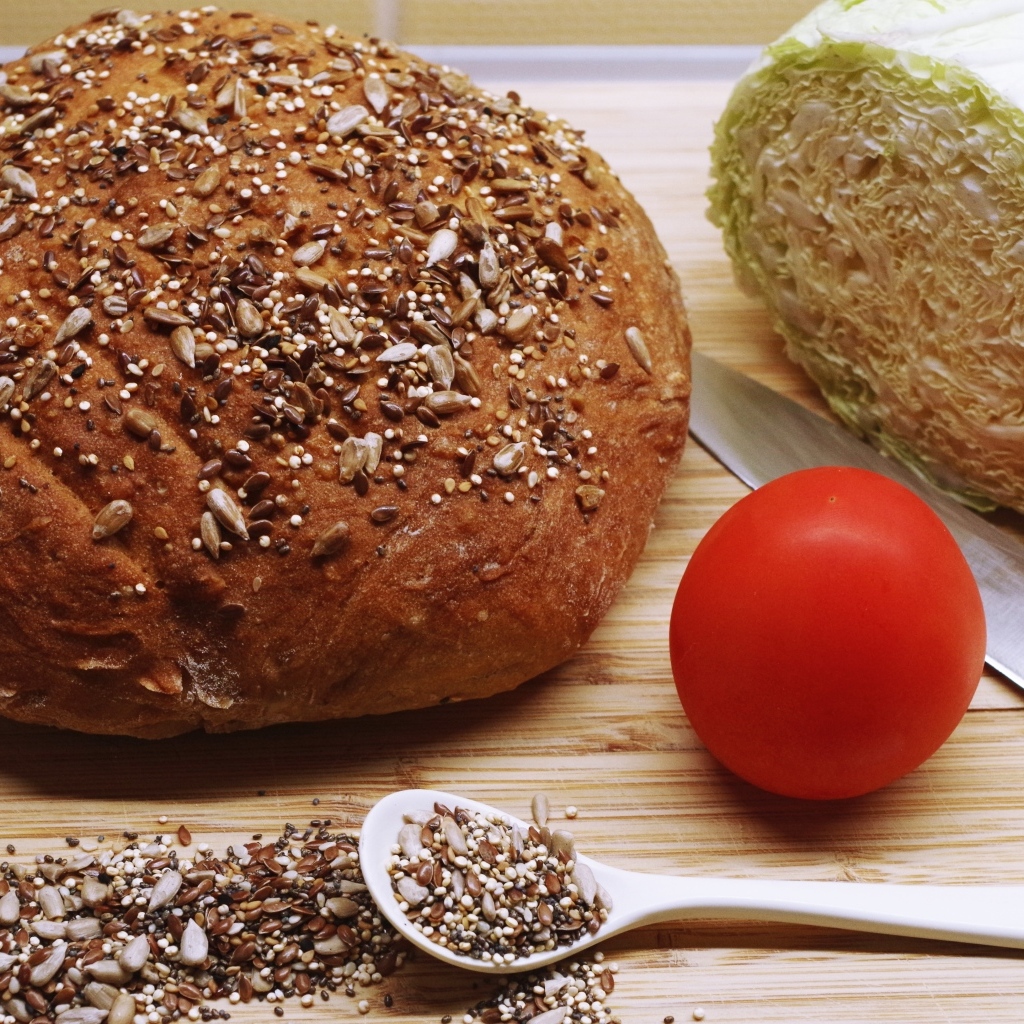 Буханка хлеба на столе с капустой и помидором