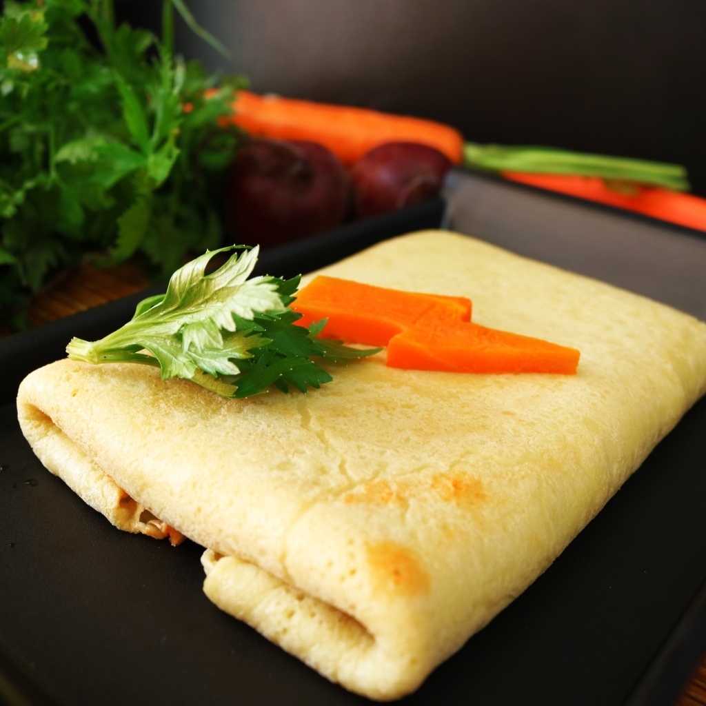 Блинчик на тарелке с морковью и веточками петрушки